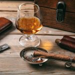 Cuban cigar and a glass of cognac brandy on wooden background